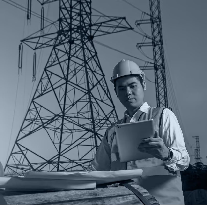 An inspector in a hard hat reviewing overhead power lines